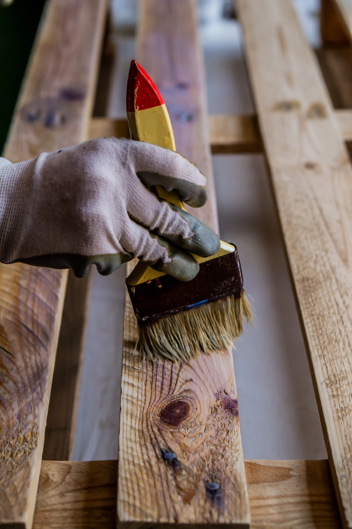 vertical-shot-person-painting-wooden-pallet-with-brush